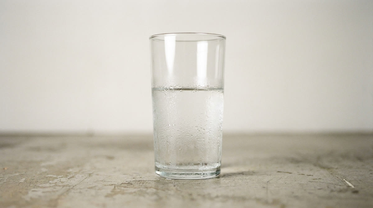 Referenzfoto: ein Glas Wasser auf einer Betonoberfläche.